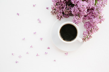 Cup of coffee and lilac branch on white textured background
