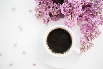 Cup of coffee and lilac branch on white textured background