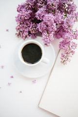Cup of coffee and lilac branch on white textured background