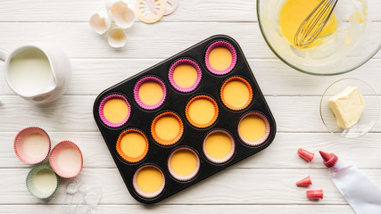top view of muffin mold with liquid dough and ingredients on table