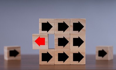 Wooden block with red arrow facing the opposite direction black arrows,Individuality and standing...