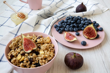 Pink bowl of fruit granola with fruits and honey, low angle view. Close-up.