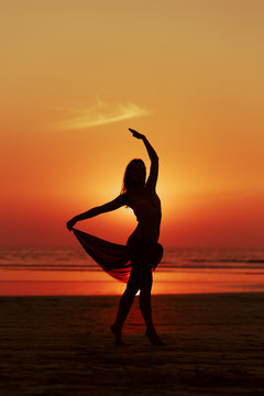 Woman dancing on the beach. Sunset and silhouette. © mishamif