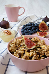 Fruit granola with fruits in a pink bowl ready to eat, side view. Closeup.