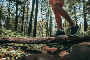 Man walking on a log in the forest and balancing: physical exercise, healthy lifestyle and harmony concept