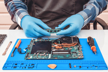 Engineer makes dismantling of RAM for disassembling and repairing a laptop.