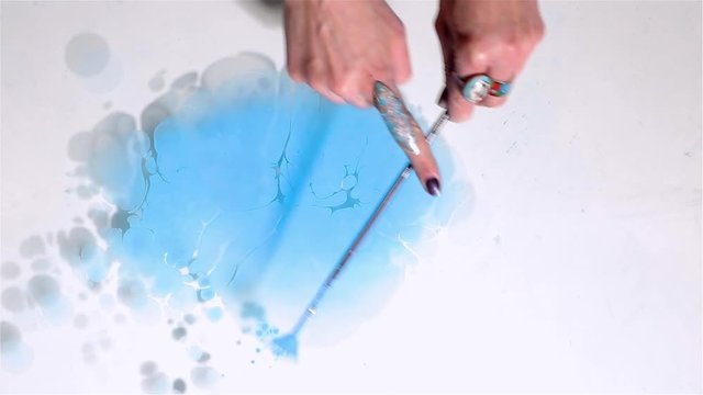 Artist creates absractive ebru design with orange, pink and white paints