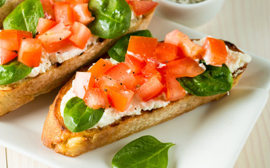 Tomato and cheese fresh made bruschetta. Italian tapas, antipasti with vegetables, herbs and oil on grilled ciabatta and baguette bread. Sandwich.