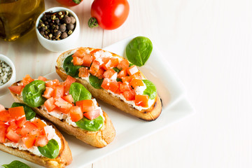 Tomato and cheese fresh made bruschetta. Italian tapas, antipasti with vegetables, herbs and oil on grilled ciabatta and baguette bread. Sandwich.