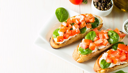 Tomato and cheese fresh made bruschetta. Italian tapas, antipasti with vegetables, herbs and oil on grilled ciabatta and baguette bread. Sandwich.