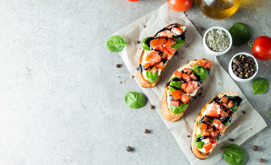 Tomato and cheese fresh made bruschetta. Italian tapas, antipasti with vegetables, herbs and oil on grilled ciabatta and baguette bread. Sandwich.
