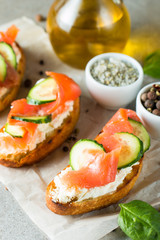 Salmon, cucumber and cream cheese bruschetta. Italian tapas, antipasti with vegetables, herbs and oil on grilled ciabatta and baguette bread. Sandwich.