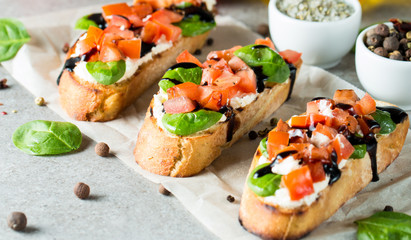 Tomato and cheese fresh made bruschetta. Italian tapas, antipasti with vegetables, herbs and oil on grilled ciabatta and baguette bread. Sandwich.
