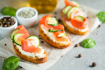Salmon, cucumber and cream cheese bruschetta. Italian tapas, antipasti with vegetables, herbs and oil on grilled ciabatta and baguette bread. Sandwich.