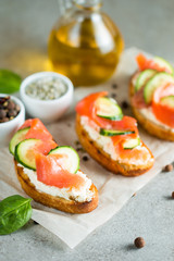 Salmon, cucumber and cream cheese bruschetta. Italian tapas, antipasti with vegetables, herbs and oil on grilled ciabatta and baguette bread. Sandwich.