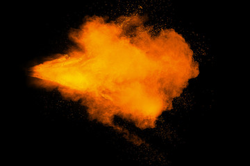 Abstract yellow orange powder explosion on black background. Freeze motion of yellow orange dust...