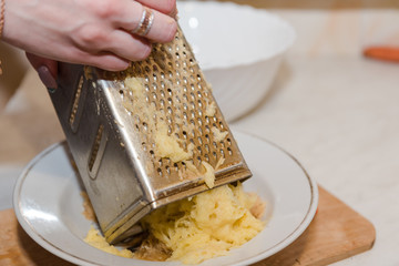 Grate the potatoes. A woman is rubbing grated potatoes. Natural food.