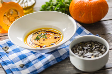 Pumpkin cream soup with seeds and parsley on kitchen table