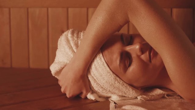 skin treatments in the sauna. a girl in a white towel on her head takes skin care procedures in a Finnish sauna.