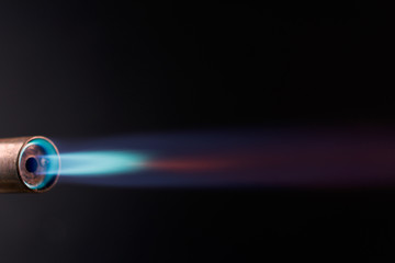 Industrial gas burner with blue and red flame, close up black background