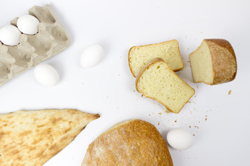 Top view of assortment of different kind of cereal bakery: bread, croissants, buns isolated on white woodden background with copy space