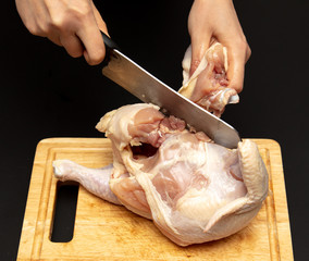 Cutting chicken carcass on a board on a black background