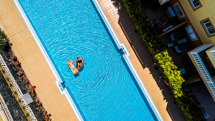 Top vertical view of swimming pool in hotel residence vacation with people adult senior lay down...