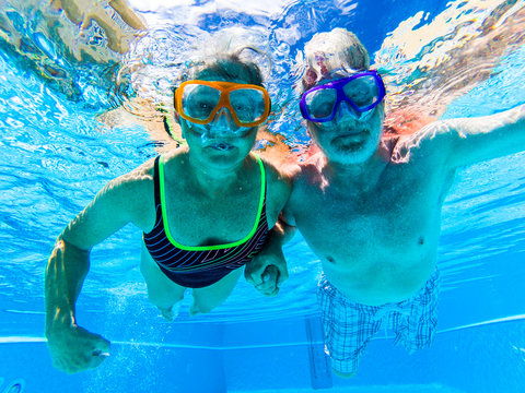 People Have Fun And Enjoy Swim Underwater In The Swimming Pool With Blue Clear Water Around - Summer Holiday Vacation Resort Hotel Concept For Tourists Aged And Retired - Active Old Senior Together