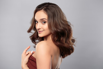 Brunette girl with healthy curly hair and natural make up . Beautiful model woman with wavy hairstyle .Care and beauty