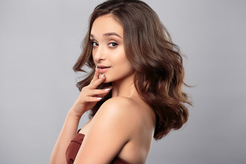 Naklejka premium Brunette girl with healthy curly hair and natural make up . Beautiful model woman with wavy hairstyle .Care and beauty