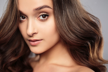 Fototapeta premium Brunetka dziewczyna z zdrowe włosy kręcone i naturalny makijaż. Piękny model kobiety z falowaną fryzurą. Pielęgnacja i uroda