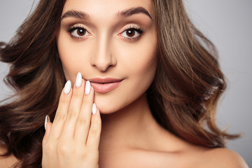 Brunette girl with healthy curly hair and natural make up . Beautiful model woman with wavy hairstyle .Care and beauty