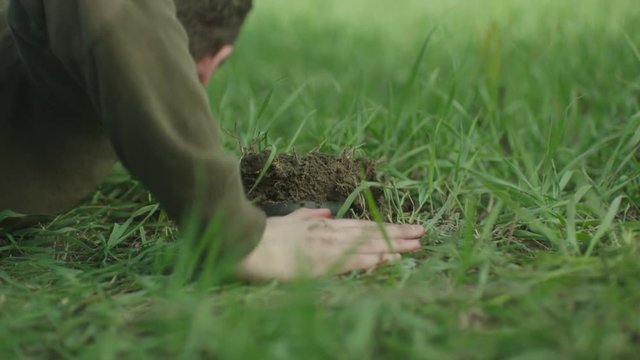 Young military is falling on the ground near the mine. Extreme close-up. 
