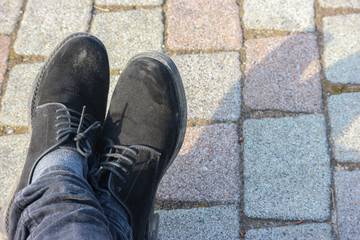 A man shoes resting on stone paving floor ground.