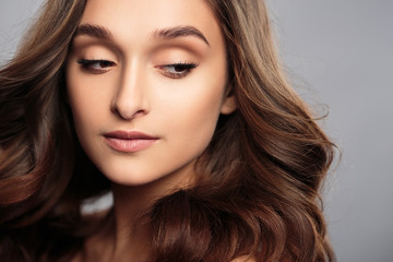 Fototapeta premium Brunette girl with healthy curly hair and natural make up . Beautiful model woman with wavy hairstyle .Care and beauty