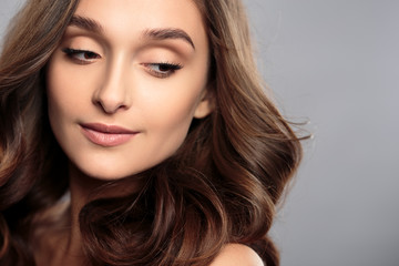 Fototapeta premium Brunette girl with healthy curly hair and natural make up . Beautiful model woman with wavy hairstyle .Care and beauty
