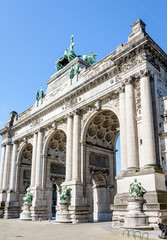 Fototapeta na wymiar Low angle view of the eastern side of the arcade du Cinquantenaire, the triumphal arch erected in 1905 by king Leopold II in the Cinquantenaire park in Brussels, Belgium, against blue sky.