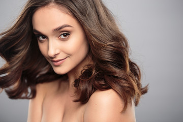 Naklejka premium Brunetka dziewczyna z zdrowe włosy kręcone i naturalny makijaż. Piękny model kobiety z falowaną fryzurą. Pielęgnacja i uroda