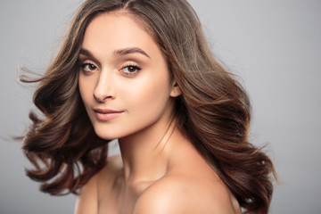 Fototapeta premium Brunetka dziewczyna z zdrowe włosy kręcone i naturalny makijaż. Piękny model kobiety z falowaną fryzurą. Pielęgnacja i uroda
