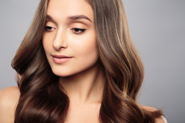 Naklejka premium Brunette girl with healthy curly hair and natural make up . Beautiful model woman with wavy hairstyle .Care and beauty