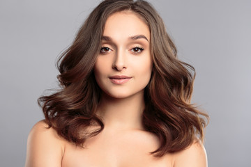 Brunette girl with healthy curly hair and natural make up . Beautiful model woman with wavy hairstyle .Care and beauty