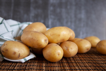 Pile of raw potatoes with textile on old wooden table.