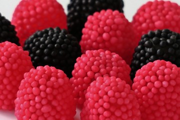jelly candies in the form of raspberries, red and black on a white background