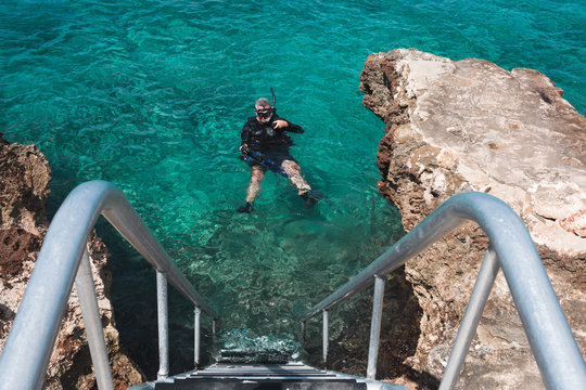 Scuba diver floating in water next to staircase in San Andres, Colombia