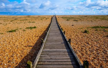 long straight wooden pathway on pebble beach