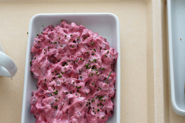 Herring salad with food coloring and buttered bread served on the tray