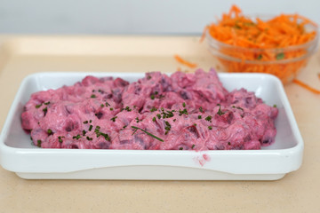 Herring salad with food coloring and buttered bread served on the tray