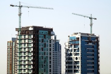 Picture of buildings under constructions with cranes on top of the structures. Construction work site background.