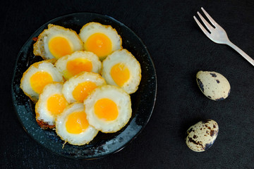 Fried quail egg on black background