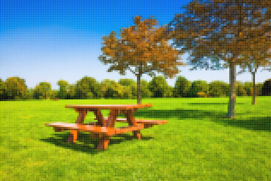 Picnic table on a green meadow with trees on background - Concept image with pixelation effect